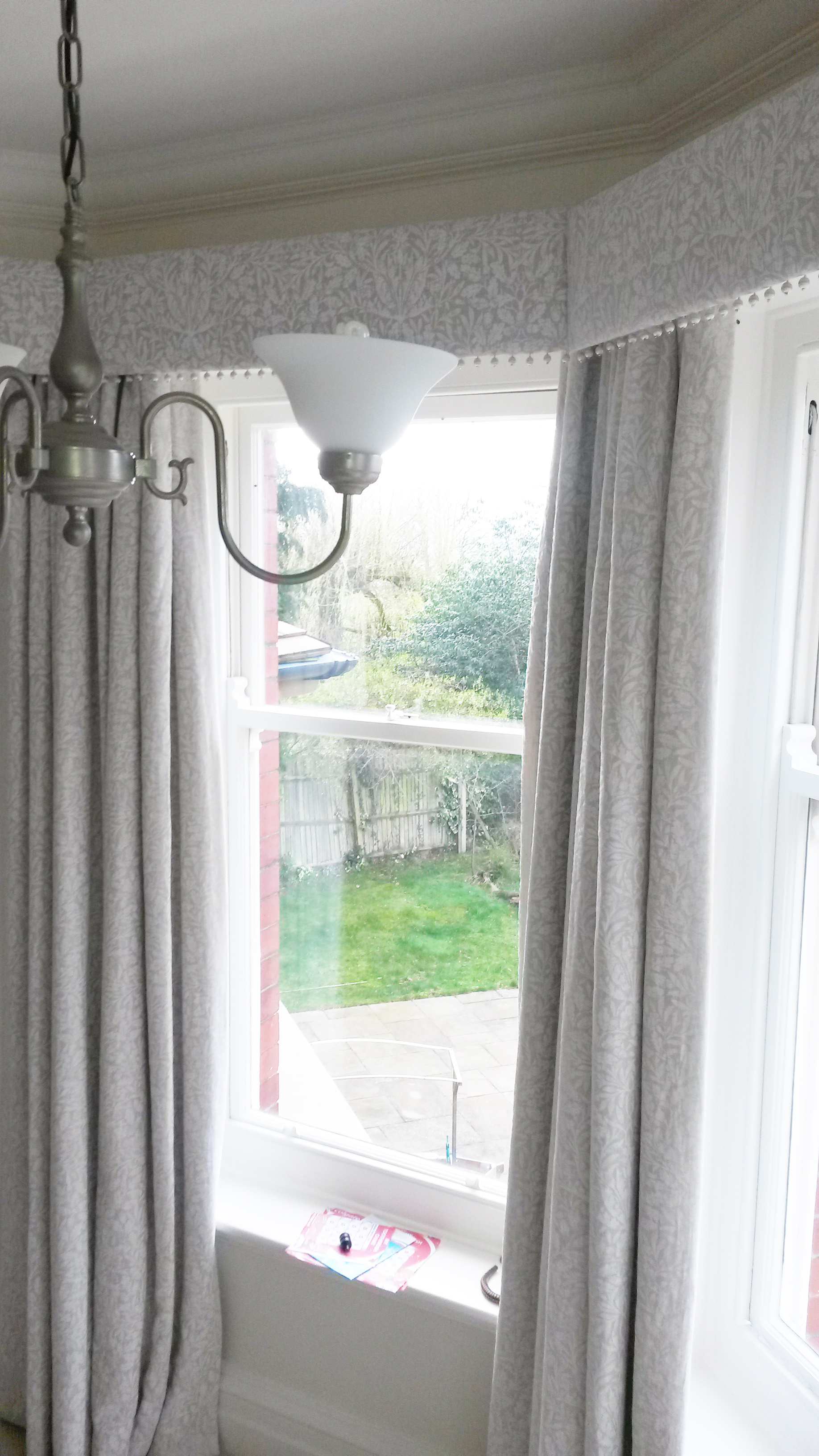 Straight pelmet with pop pom trim in bay window. Morris and Co Pure fabric